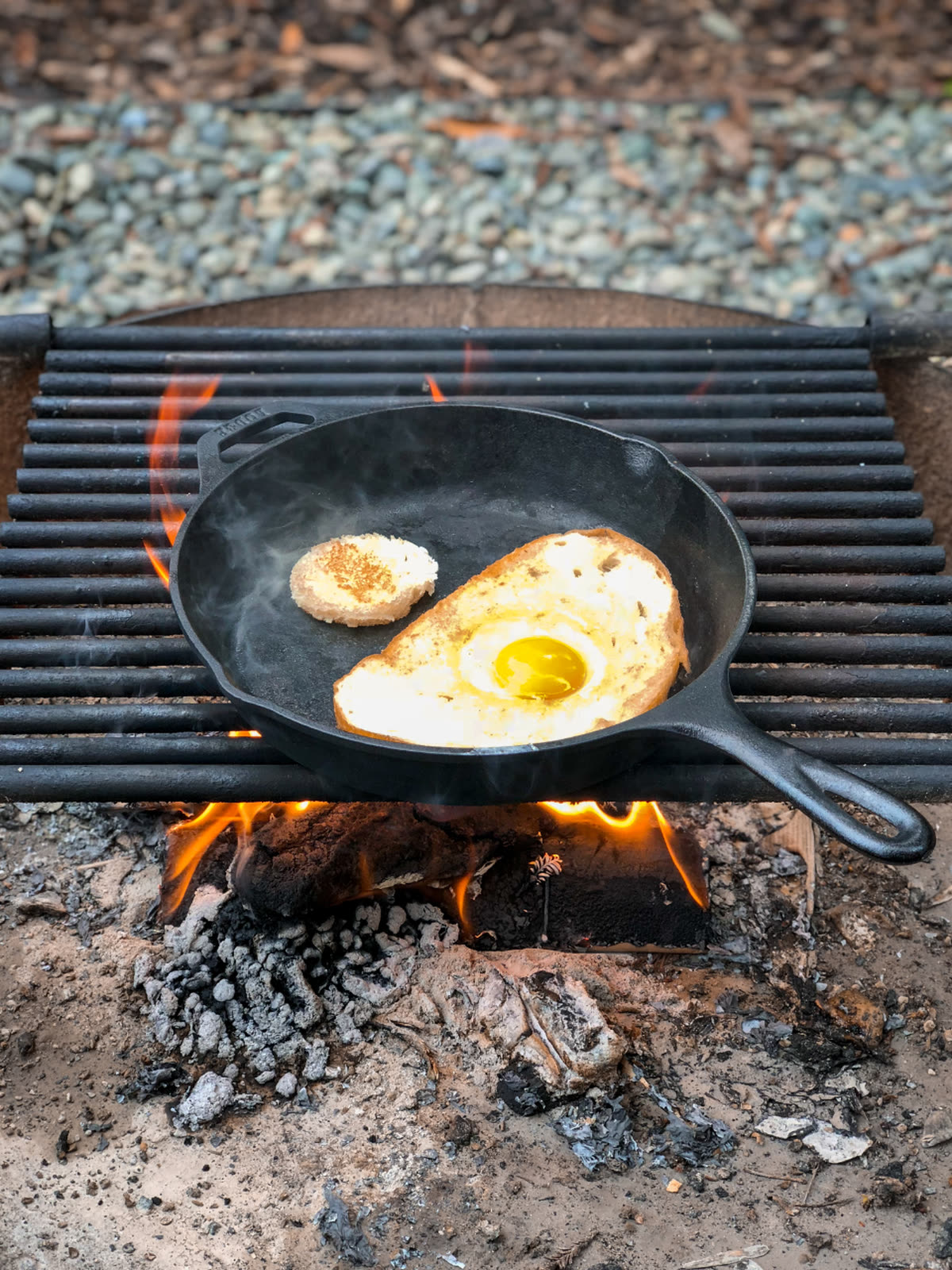 A fried egg cooking in a cast-iron skillet over an open flame